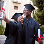 Black students, hug and celebration for graduation, education and achievement on university, campus and success. African American woman, man or academics with smile, embrace or joy for college degree